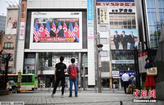 资料图：2018年6月，在日本东京的一个广场，人们通过户外大屏幕观看朝美领导人首次会晤的直播画面。