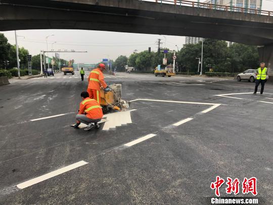 工作人员给事发路段的地面喷上白色的交通标线。 孙权 摄