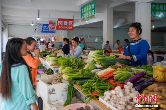 贵州省榕江县易地扶贫搬迁安置点卧龙小区，侗族妇女石本艳(右一)在菜市场卖菜。<a target='_blank' href='http://www.chinanews.com/'>中新社</a>记者 贺俊怡 摄